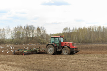 The tractor plows the field in the spring