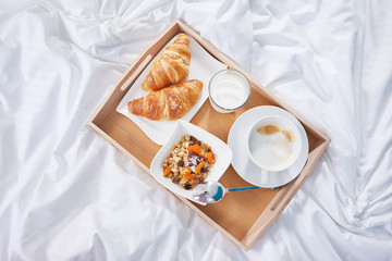 breakfast in bed with coffee and croissants. top view