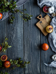 Muffins with blood oranges on a white wooden stand with green leaves, cloth and wooden desk on a black background