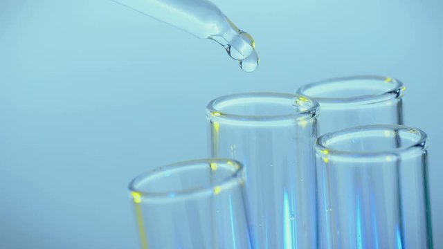 Pipette drips clean chemicals into a test tube. Close-up shot.
