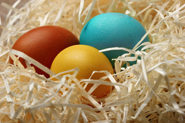 Fototapeta na wymiar Easter eggs in nest on wooden background, close-up.Selective focus
