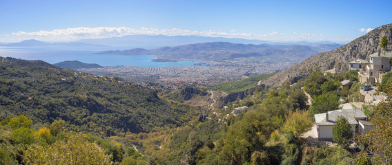 Panoramic top view on Mediterranean Sea bay with city on bottom and distant islands in back lit. Volos, Greece.
