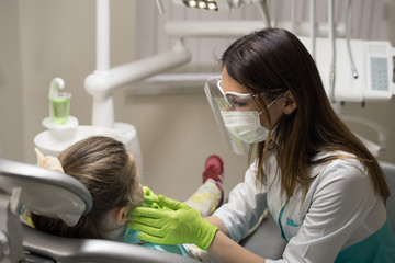 Female Dentist checking little girl patient at dental clinic.