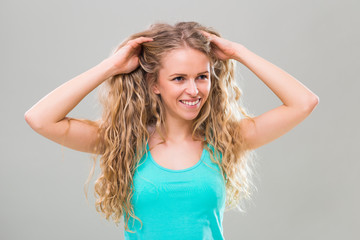 Fototapeta premium Portrait of young woman with gorgeous long blonde hair on gray background.