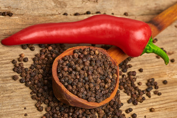 Closeup Red hot chili peppers and black pepper whole in wooden spoon on old wooden background