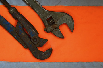 Adjustable and pipe wrenches against the background of an orange signal worker shirt