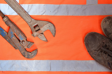 Adjustable and pipe wrenches against the background of an orange signal worker shirt