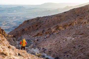Man guy tourist backpacker standing looking view desert mountain peak.