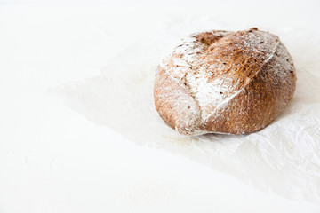 A loaf of homemade bread in a paper on a white background with space for your text.