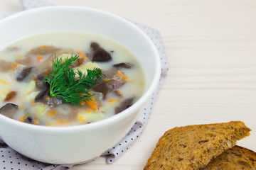 Mushroom cream soup with chopped dill and whole grain bread on wooden table