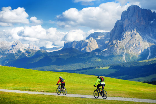 Tourists cycling in Seiser Alm, the largest high altitude Alpine meadow in Europe, stunning rocky mountains on the background.