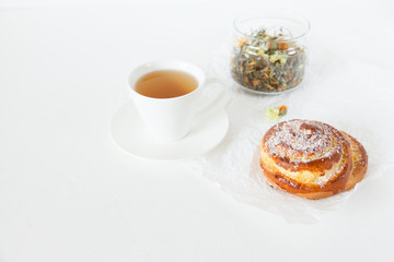 Herbal tea and sweet buns with sugar and cinnamon on a white background.