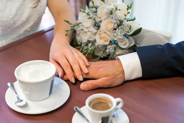 Hands of lovers, men and women hold each other. Couple in a cafe for drinking coffee.