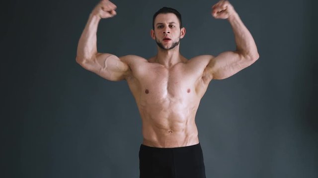 bodybuilder flexing his muscles at studio, dark grey background