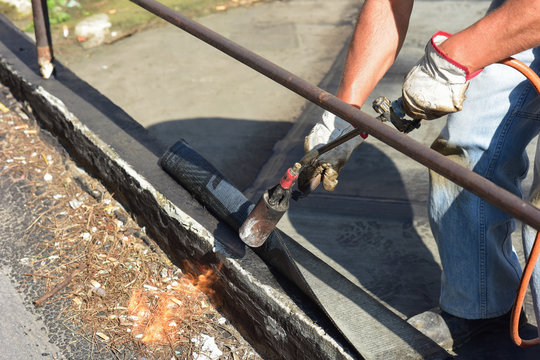 Lavori di costruzione con feltro per pavimentazione stradale, con riscaldamento e fusione di feltro bituminoso per coperture.