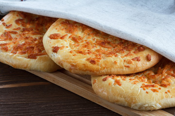 Round pies with cheese covered with linen napkin