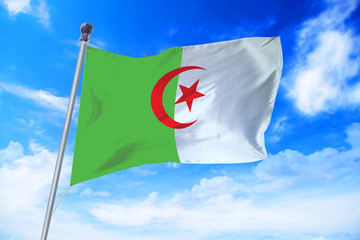 Flag of Algeria developing against a clear blue sky