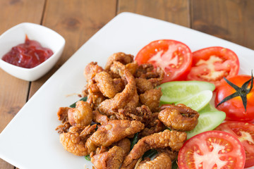Deep-fried chicken skin in white dish with tomato sauce thai food