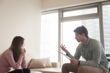 Fototapeta premium Young lady crying, holding a handkerchief sitting on the couch while consulting by male psychologist. Therapist talking to sad depressed woman in tears, helping her to find the answers