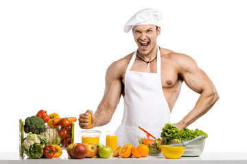 Man bodybuilder cook, cooking freshly squeezed juice and vegetables salad