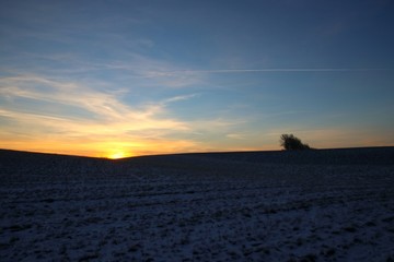 The sun rises behind a hill in February