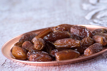  Useful food. Dried sweet dates on a round copper tray.