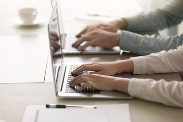 Man and woman working together on two laptops at home office interior. Close up view of female and male hands on keyboard, online support, educational on-line courses  concept
