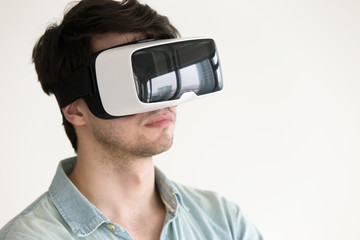 Portrait of serious young man testing 3d virtual reality headset for studying and entertainment, immersing into visual world, travel experience using apps for vr simulator, watching 360 degrees video