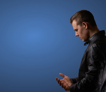 Profil shot from a young man in leatherjacket, rubbing his hand with copyspace