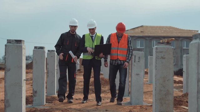 The architect and workers go on incomplete building and discuss the plan and deadline of construction. Aerial 4K stabilized shot