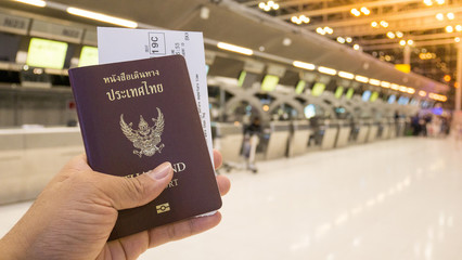 Tourist hold passport and boarding pass at the counter for check-in and travel in the airport. Passport and boarding pass for travel concept.