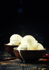 Vanilla ice cream with ground cocoa in brown bowls, dark background, selective focus