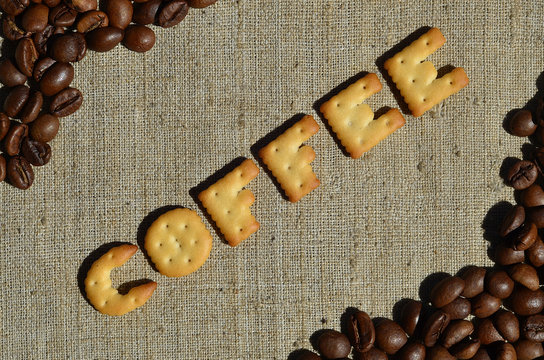 Fototapeta Coffee. The word from the edible letters lies on the gray canvas with coffee beans