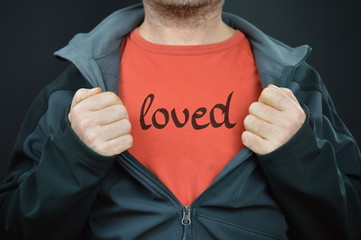 a man showing his t-shirt with the word loved on it