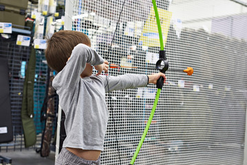 Little boy shoots by bow in children's shooting range