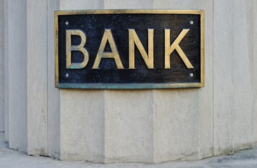 A vintage BANK sign on a column in front of a bank