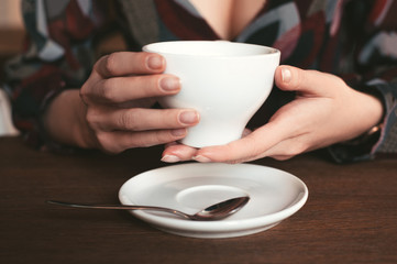 woman sitting in a cafe in the morning and gently holding a cup of coffee in hand