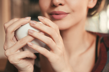 woman holding a cup tea in hand, sitting in the morning in a cafe