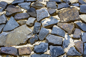 Stone old wall texture. Old rock blocks in old medieval brick. Exterior historical country situation with fencing. Village rural foundation background.