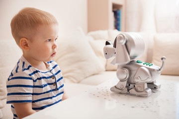 Adorable toddler boy playing with interactive toy. Child with toy robot dog. indoors. Activities for small children. Communication and digital concept.