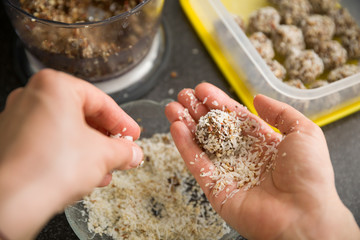 Closeup of woman's hands making healthy sweet treats. Cooking chocolate protein balls with nuts and...
