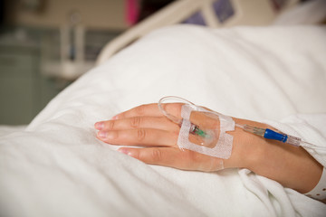 Close up hand of young patient with intravenous catheter for injection plug in hand during lying in the hospital bed. - obrazy, fototapety, plakaty