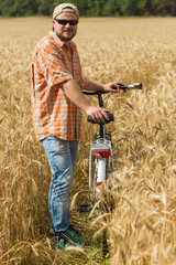 Traveller in cap and sunglasses with a bicycle at the field