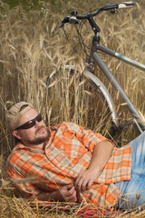 Matured traveller in cap and sunglasses having a res