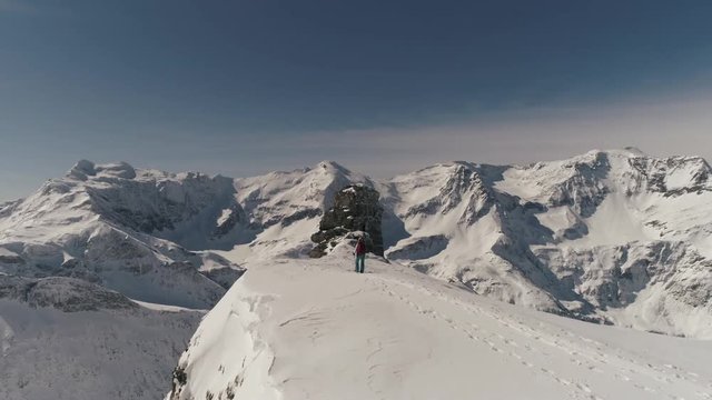 Female trakker reaching top of snowy mountain