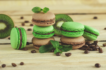 Green and brown french macarons with kiwi, coffee beans and mints decorations