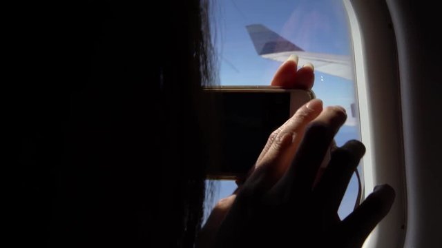 4k Young beautiful asian woman interior airplane. A passenger on a plane using device smart phone to take a picture the views out window in the airport-Dan