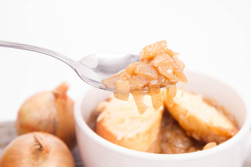 Onion soup with toast on a wooden background with some onions and garlic