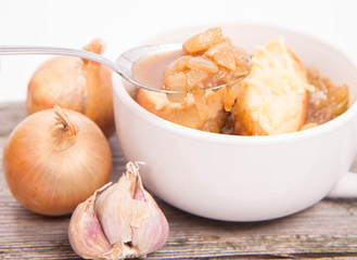 Onion soup with toast on a wooden background being eaten with a spoon