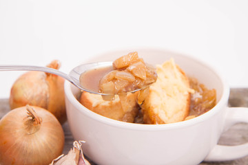 Onion soup with toast on a wooden background being eaten with a spoon